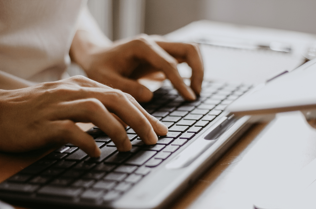 Photo of hands typing on a computer keyboard, representing using AI medical advise and the risks