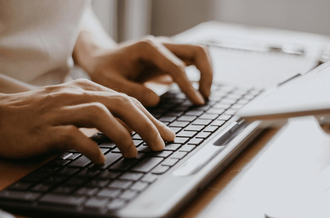 Photo of hands typing on a computer keyboard, representing using AI medical advise and the risks